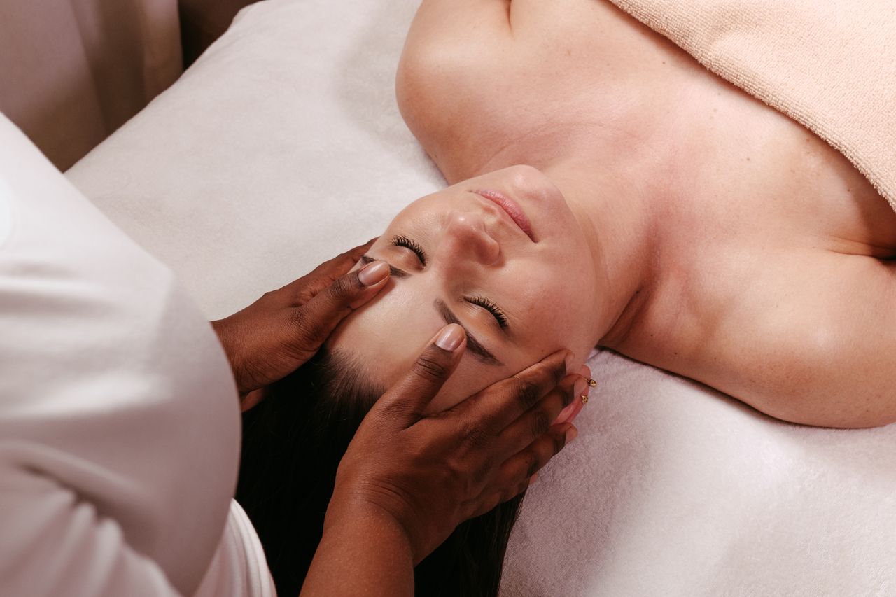 Home A woman enjoys a serene head massage in a spa setting, promoting wellness.